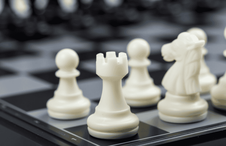 A detailed shot of white chess pieces on a modern black board, focusing on the rook