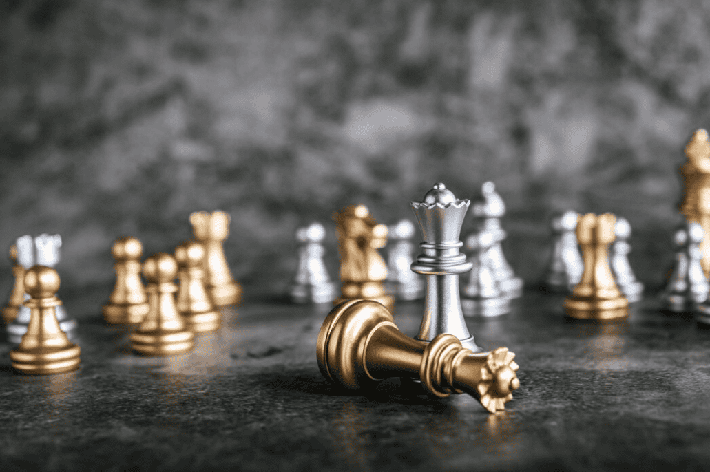 gold and silver chess on marble black table in front of black and white marble background